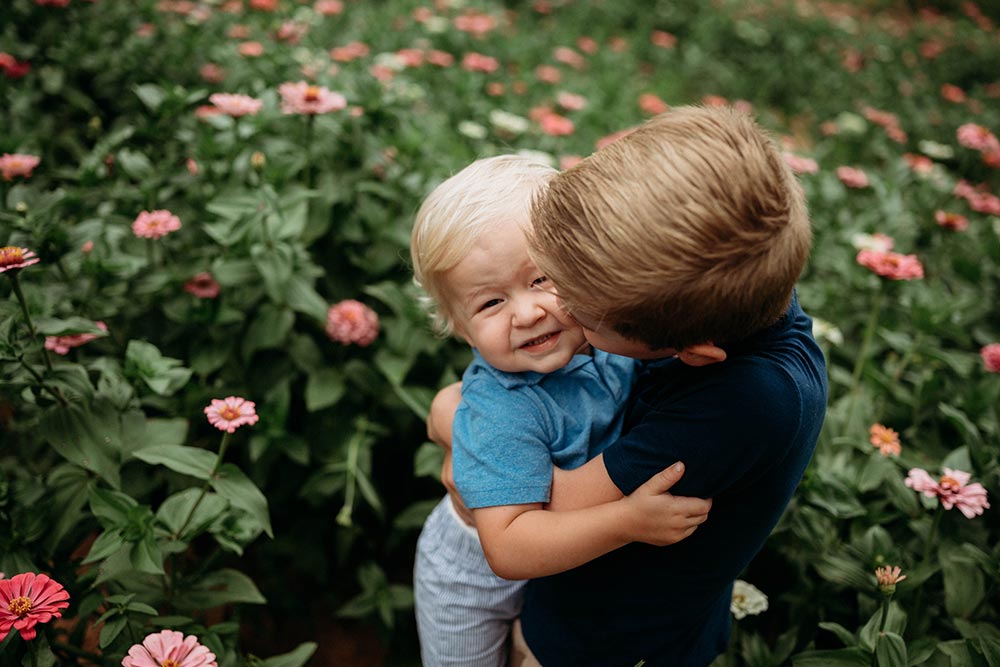 Children hugging in a pink zinnia field at Firefly Haven in Hamptonville, NC. Taken by Karena Schroeder Photography.