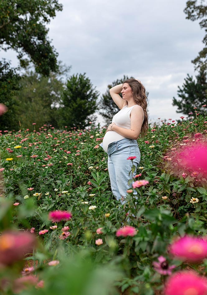 Maternity photoshoot within the pink and white zinnia field at Firefly Haven. Taken by Photography by Melody.