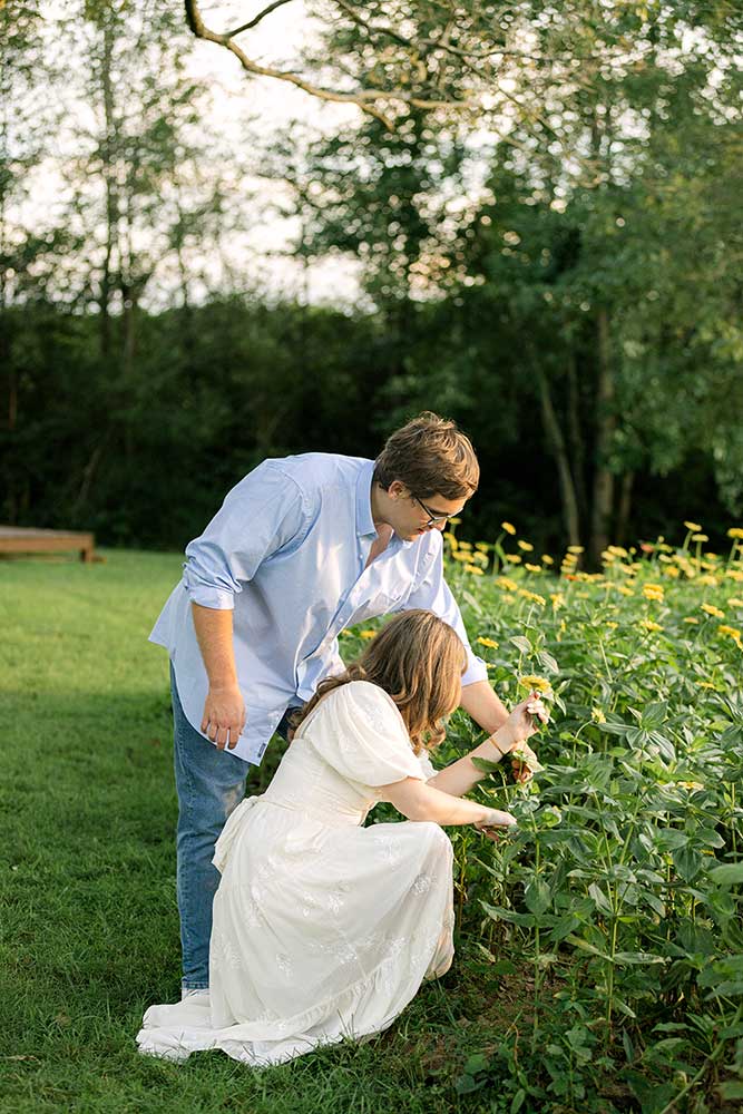 An engaged couple cutting yellow zinnias for a bouquet at Firefly Haven in Hamptonville, NC. Taken by Ashley Logan Photography.